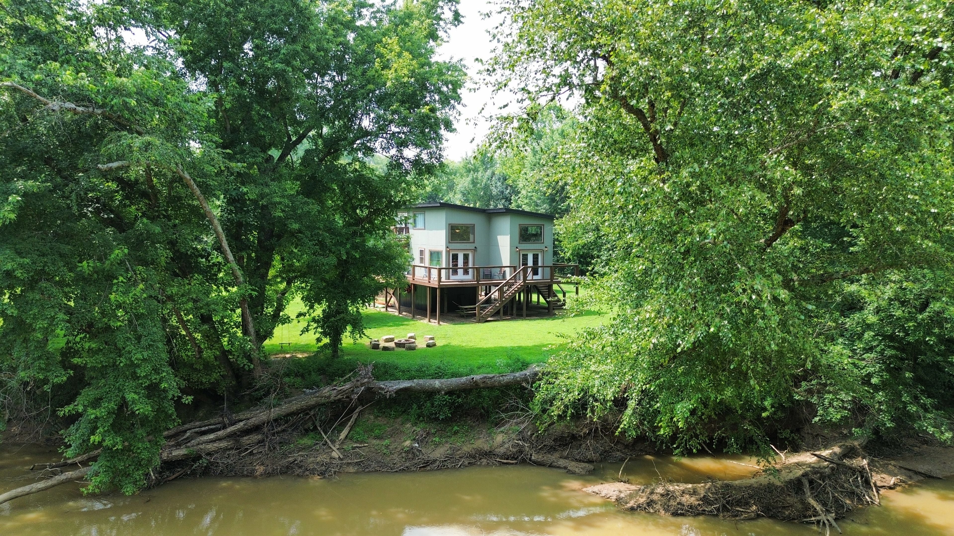 Una casa rodeada de abundante vegetación y un río.