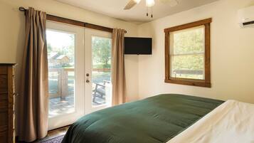 A bedroom with a bed, a ceiling fan, a TV, and a window with blinds.