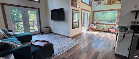 Een ruime woonkamer met een grote bank, een salontafel en een keukenhoek met een fornuis.