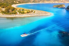 A coastal resort with a circular beach area, a boat in the water, and a mountainous backdrop. - Mira Stay Apartment with Pool in Ölüdeniz (Ölüdeniz)