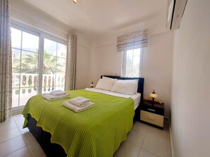 A hotel room with a bed, a nightstand, a lamp, and a view of the outdoors. - Mira Stay Apartment with Pool in Ölüdeniz (Ölüdeniz)