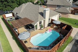 A residential backyard with a swimming pool, patio furniture, and a fenced deck area. - POOL , MINI GOLF & OUTDOOR MOVIE THEATER (McKinney)