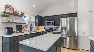 Une cuisine moderne avec des meubles de couleur sombre, des appareils électroménagers en acier inoxydable et un îlot central.