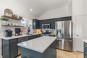 A modern kitchen with dark cabinetry, stainless steel appliances, and a central island.