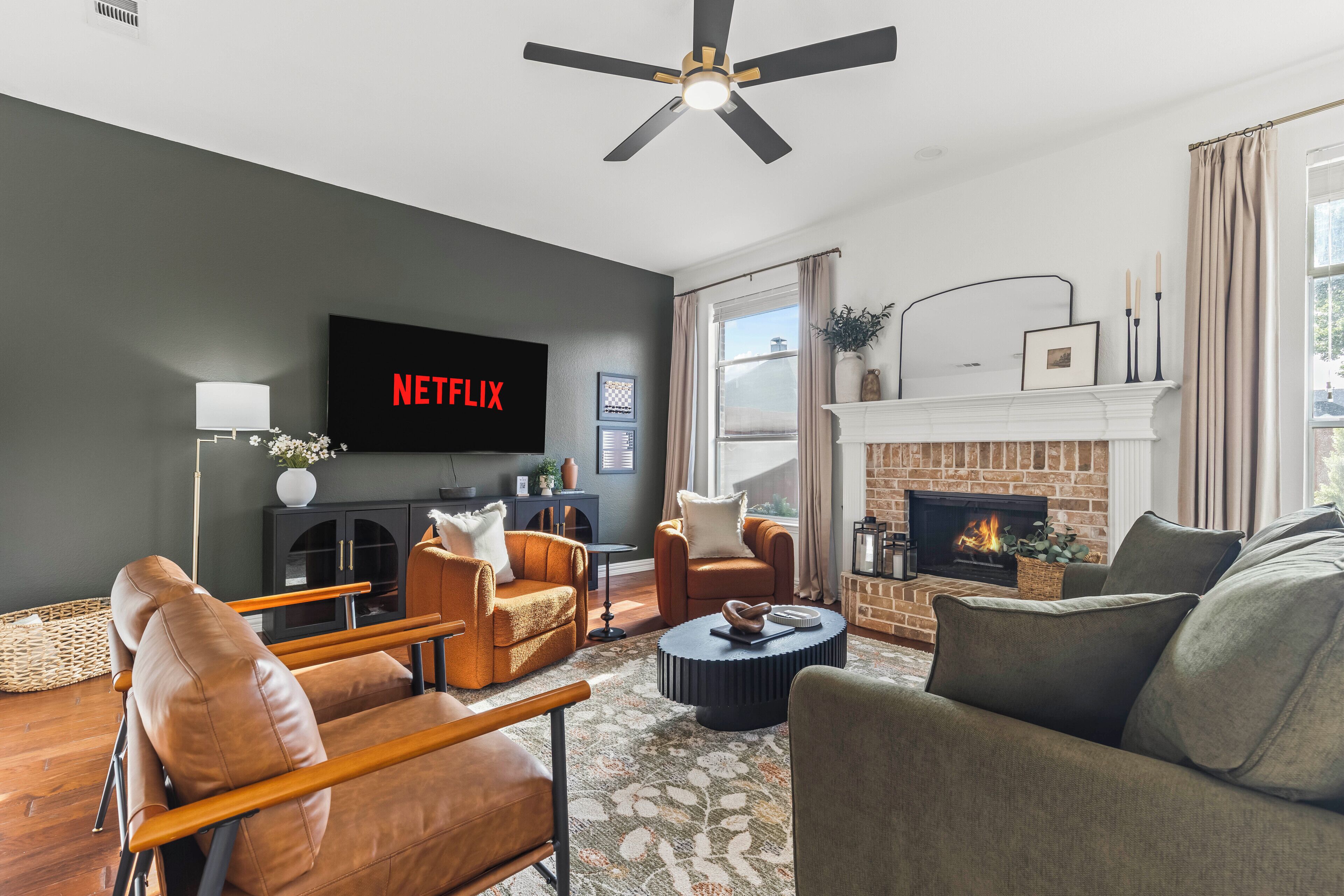 Un salon moderne doté d’une cheminée, de sièges confortables, d’un téléviseur à écran plat et d’un ventilateur de plafond.