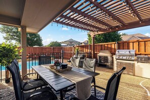 A covered outdoor patio with a pool, barbecue grill, and seating area. - POOL , MINI GOLF & OUTDOOR MOVIE THEATER (McKinney)
