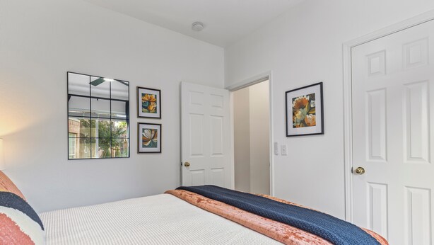 A bedroom with a bed, two doors, and three framed pictures on the wall. - POOL , MINI GOLF & OUTDOOR MOVIE THEATER (McKinney)