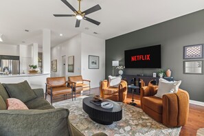 A modern living room with a flat-screen TV, leather sofas, a coffee table, and a ceiling fan. - POOL , MINI GOLF & OUTDOOR MOVIE THEATER (McKinney)