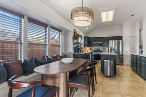 A modern kitchen with a central island, built-in appliances, and a dining area with a bench and chairs. - POOL , MINI GOLF & OUTDOOR MOVIE THEATER (McKinney)