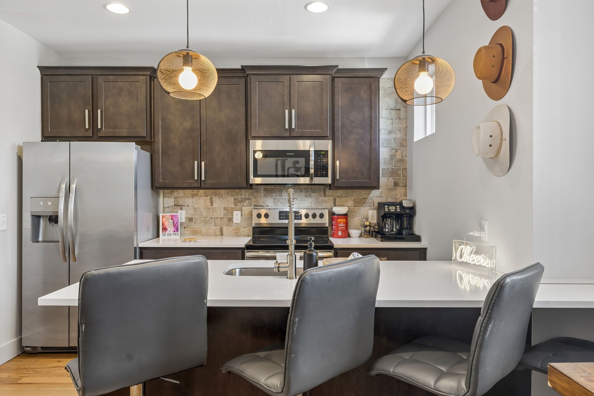 A modern kitchen with dark wood cabinets, stainless steel appliances, and a central island with seating.
