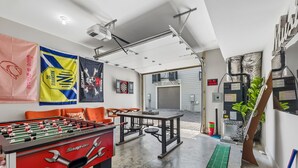 Una stanza con un tavolo da calcio, un bersaglio da freccette e un tavolo da ping pong.
