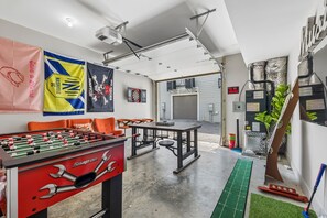Ein Zimmer mit Kicker, Dartscheibe und Tischtennisplatte.