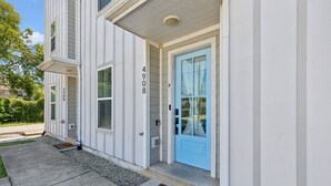 Un edificio residenziale con una porta d'ingresso azzurra, il numero '4908' sulla parete e un tappetino d'ingresso con la scritta 'Key Up'.