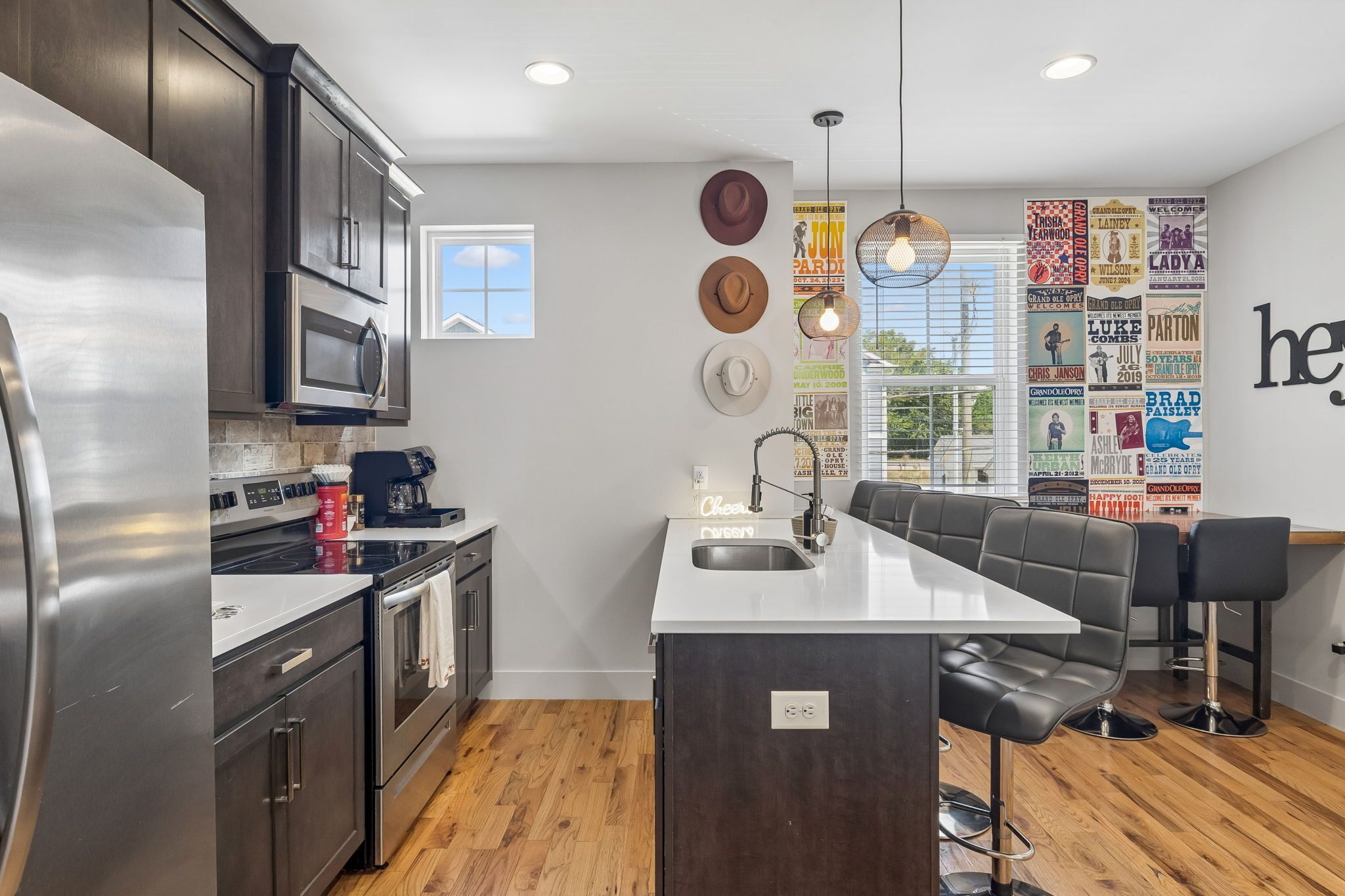 A modern kitchen with a central island, stainless steel appliances, and a seating area with bar stools.