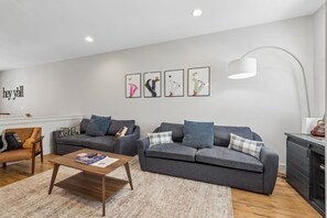 Ein modernes Wohnzimmer mit einem grauen Sofa, einem Holztisch und einer Gitarre.