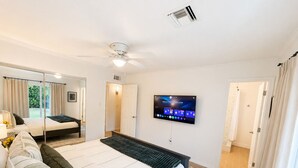 A modern bedroom with a bed, a TV, a ceiling fan, and a large mirror. - Walk to Old Town • Pool • Golf • Sleeps 10 (Scottsdale)
