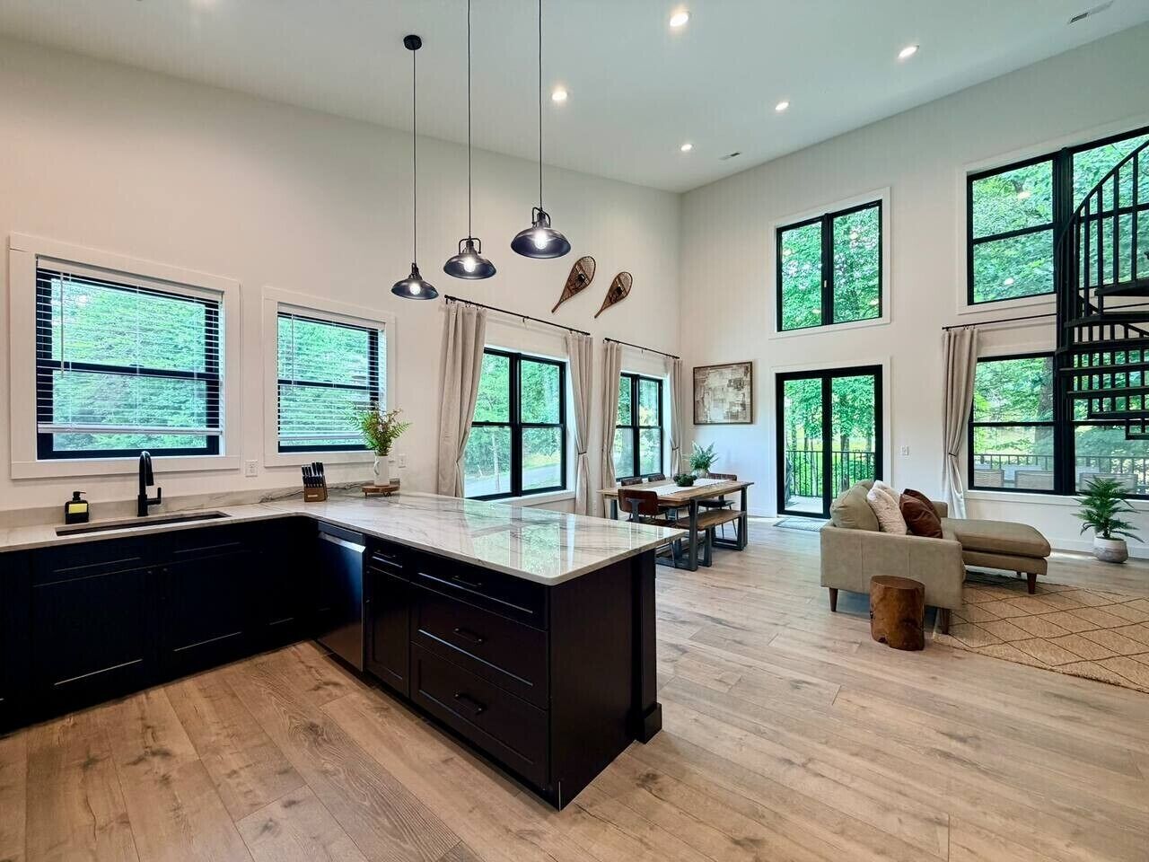 A modern kitchen with a large island, dining area with a table and chairs, and a living area with a sofa.