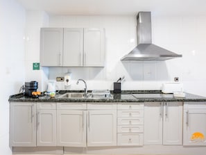 A kitchen with white cabinets, a stainless steel range hood, a granite countertop, a coffee maker, a toaster, and a soap dispenser. - Balcon de Santa Maria Free Parking by Cadiz Time (Provincia de Cádiz)