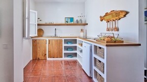 A compact kitchen with wooden cabinets, a white countertop, and a fish-shaped wall decoration. - New penthouse with a private terrace in the heart of Cádiz. (Ciudad de Cadiz)