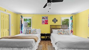 A room with two beds, a ceiling fan, and a window with curtains.