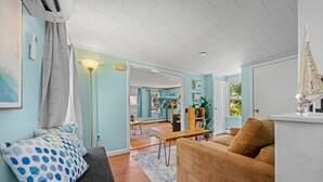 Una sala de estar con un sofá, una mesa de centro y una lámpara. Hay una puerta que conduce a otra habitación.