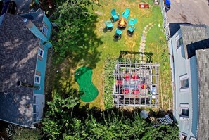 Luftaufnahme eines Wohngebiets mit Schwimmbad, Außenbereich zum Sitzen und einem eingezäunten Spielplatz.