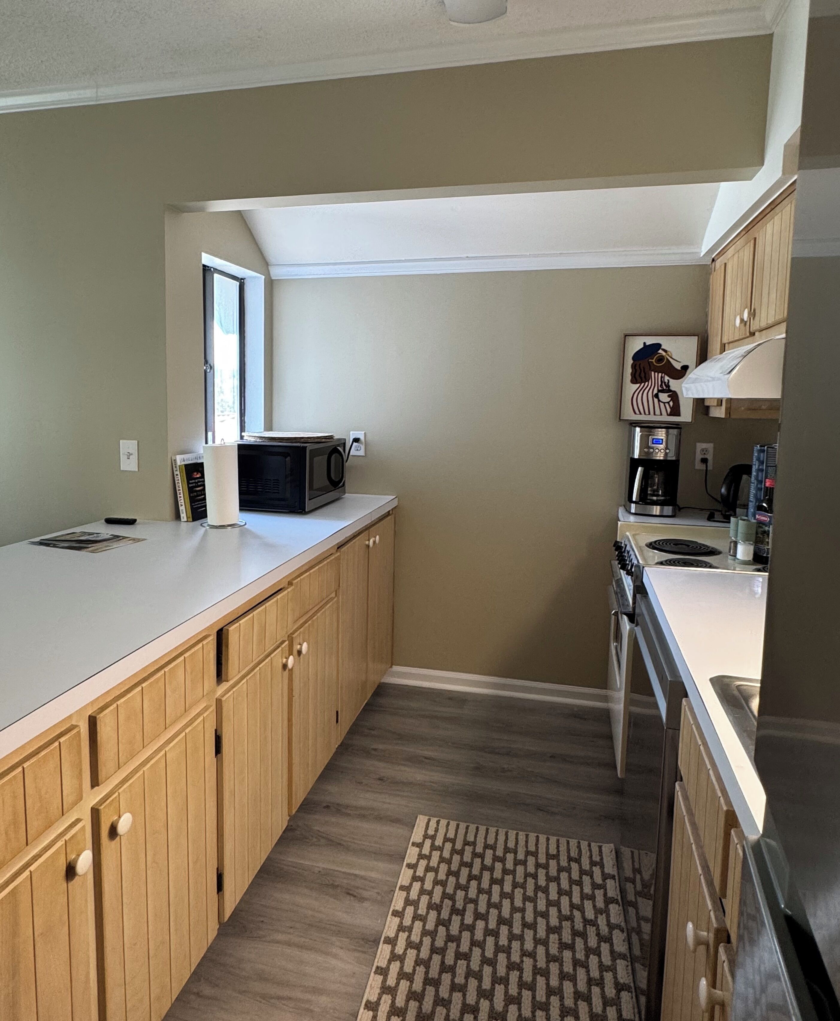 A compact kitchen with wooden cabinets, a microwave, a coffee maker, and a refrigerator.