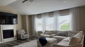 Ein Wohnzimmer mit Kamin, einer Couch, einem Relaxsessel und einem Fernseher.