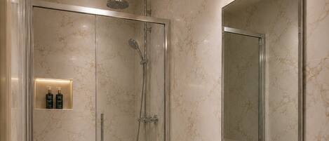 A modern bathroom with a glass-enclosed shower, a white sink, and a large mirror.