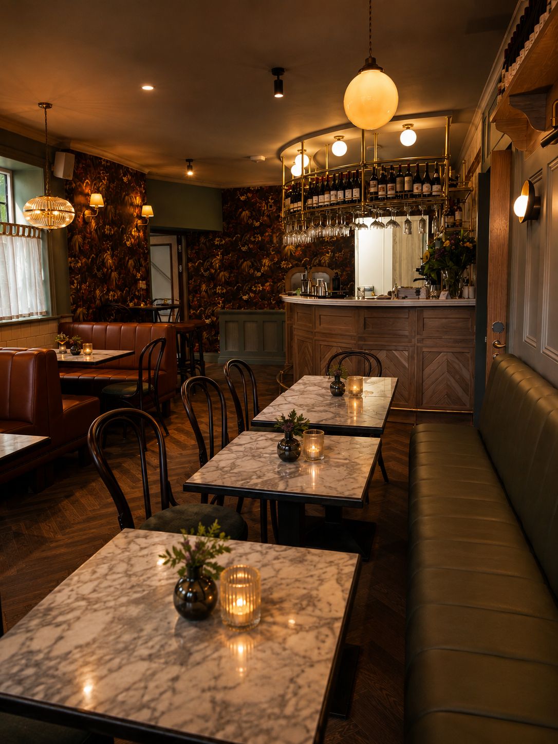 Ein Restaurantinneres mit Marmortischen, Ledersitzbänken und einer Bar mit Flaschen und Gläsern.