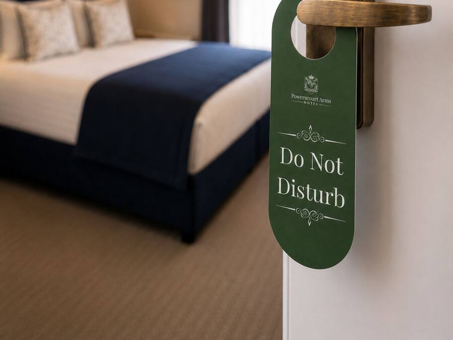 Habitación de hotel con cama, manija en la pared y un cartel de 'No molestar'.