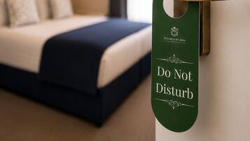 A hotel room with a bed, a wall-mounted door with a 'DO NOT Disturb' sign, and a pendant light.