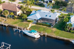 A waterfront property with a boat dock, a house with a large glass window, and a well-maintained lawn. - Sunsets & Serenity: Waterfront Canal Home w/ Saltwater Pool in Punta Gorda Isles (Punta Gorda)