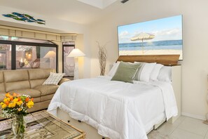 A bedroom with a bed, a sofa, a lamp, a vase with flowers, and a beach view painting. - Sunsets & Serenity: Waterfront Canal Home w/ Saltwater Pool in Punta Gorda Isles (Punta Gorda)