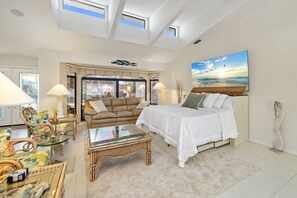 A spacious room with a large bed, a sofa, a glass coffee table, and a view of the sea through a large window. - Sunsets & Serenity: Waterfront Canal Home w/ Saltwater Pool in Punta Gorda Isles (Punta Gorda)