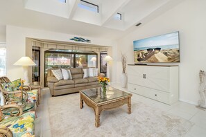 A spacious living room with a glass coffee table, a sofa, and a large TV. - Sunsets & Serenity: Waterfront Canal Home w/ Saltwater Pool in Punta Gorda Isles (Punta Gorda)