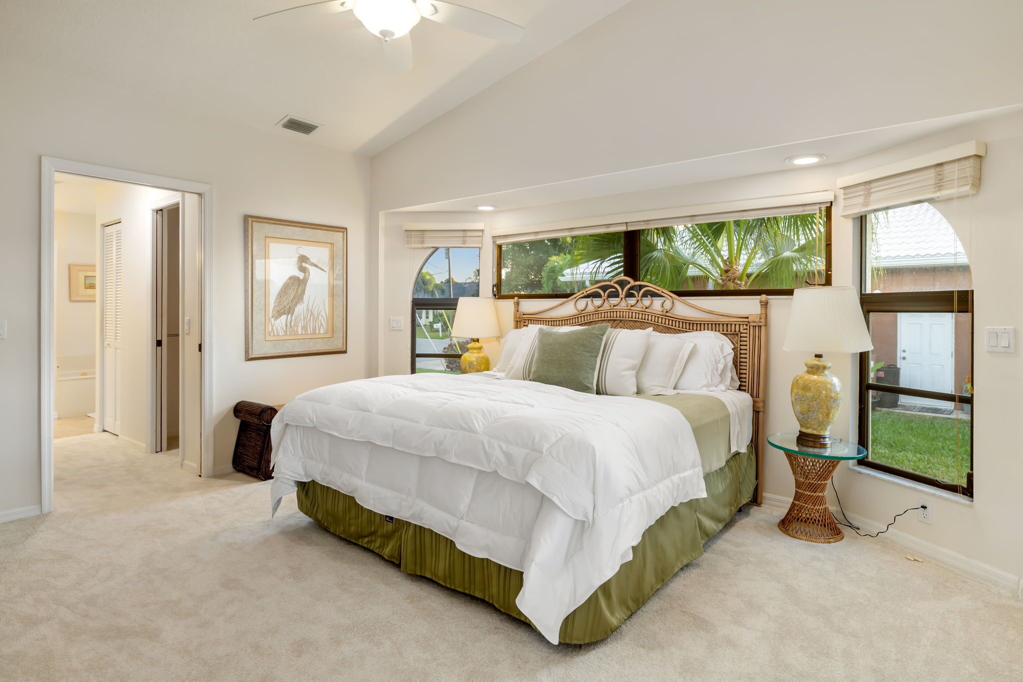 Un dormitorio con cama, ventana con vistas, lámpara y un cuadro en la pared.