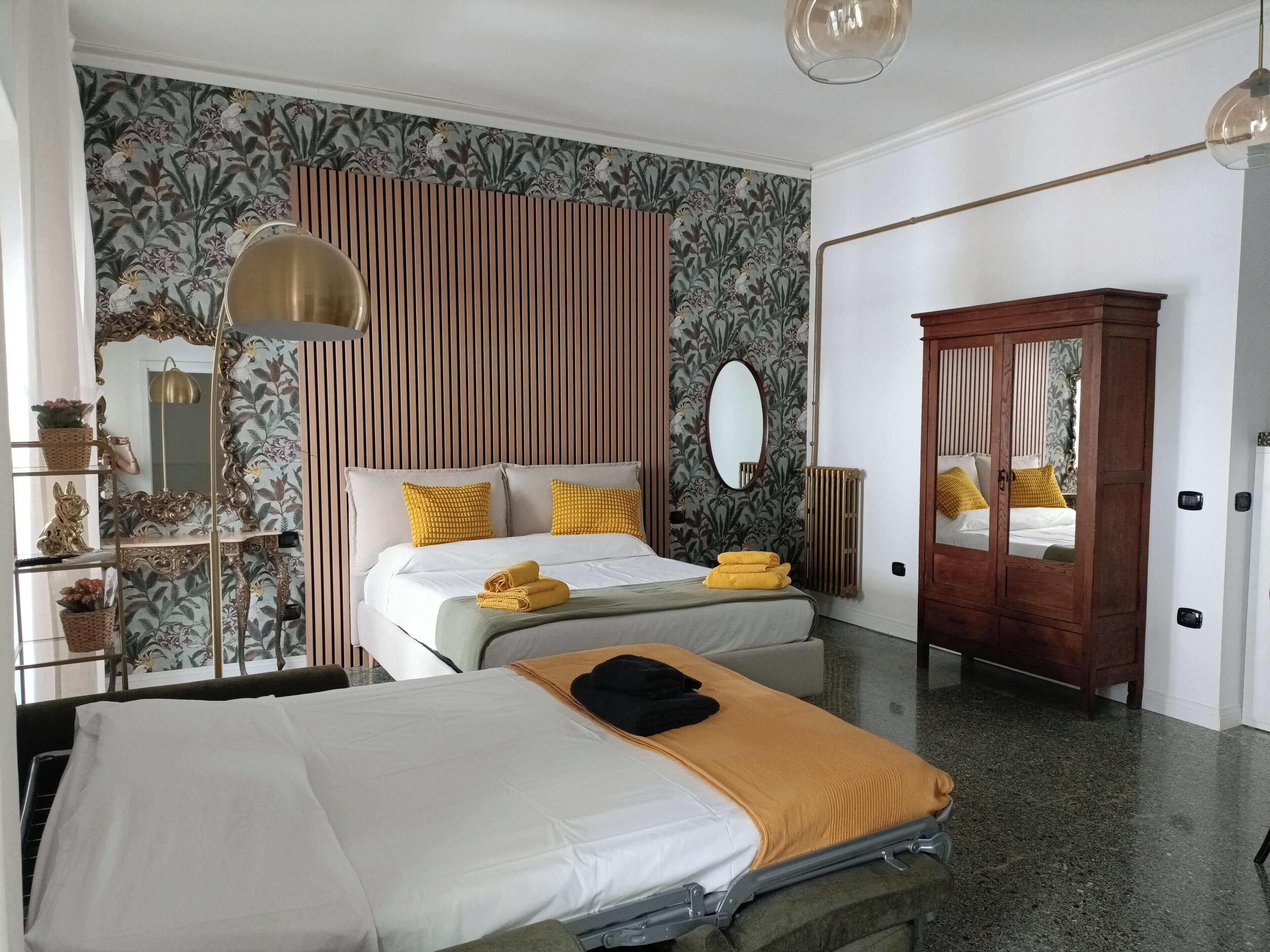 A hotel room with a bed, bedside table, lamp, wardrobe, and a mirror.