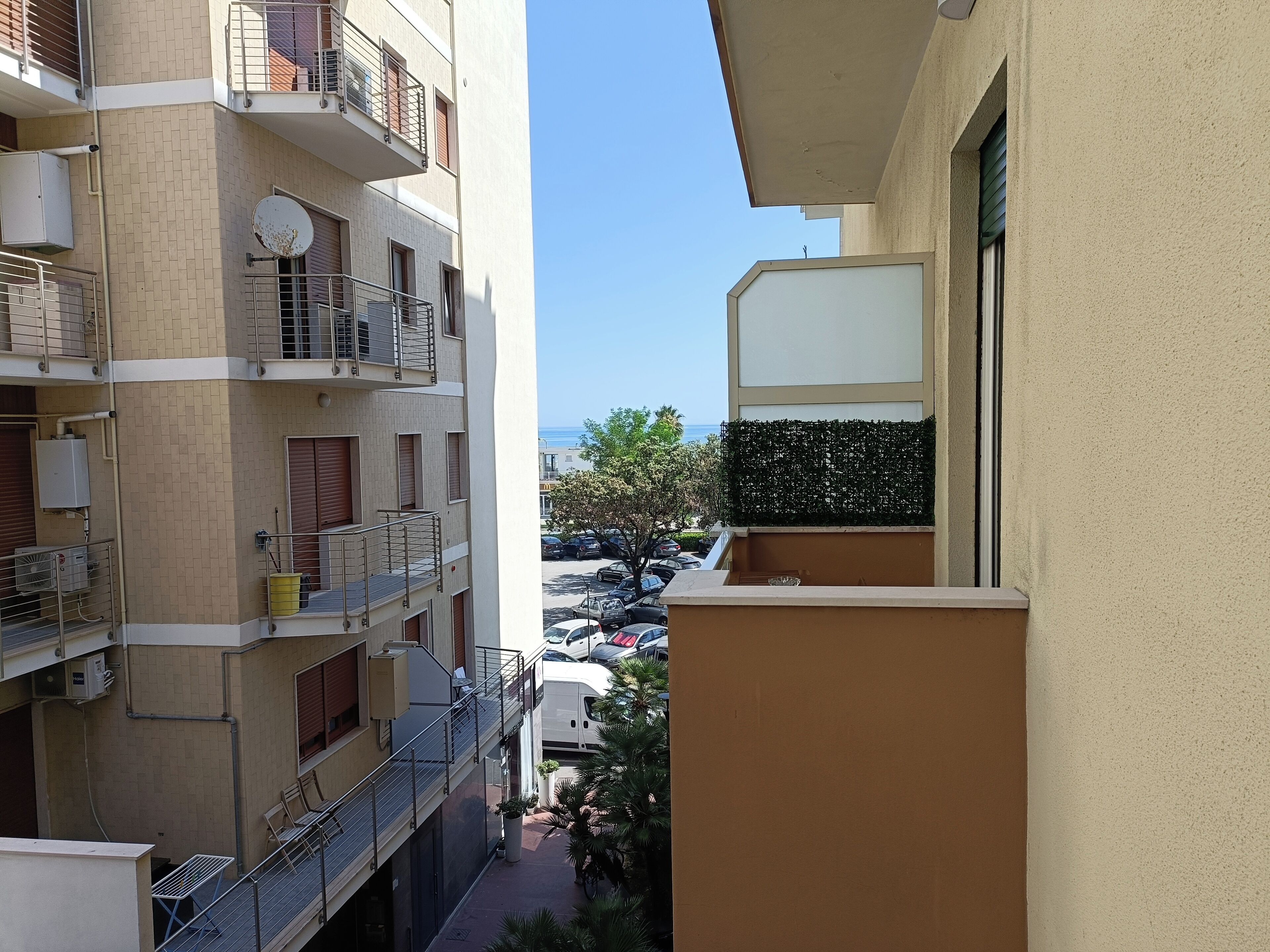 Ein mehrstöckiges Wohngebäude mit Balkonen, einem Parkplatz und Blick auf das Meer.