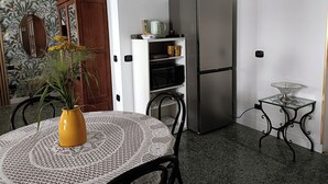 A compact kitchen with a refrigerator, a small table with a lace tablecloth, and a potted plant. - CIATTONI GUEST HOUSE STUDIO SUITE (Pescara)