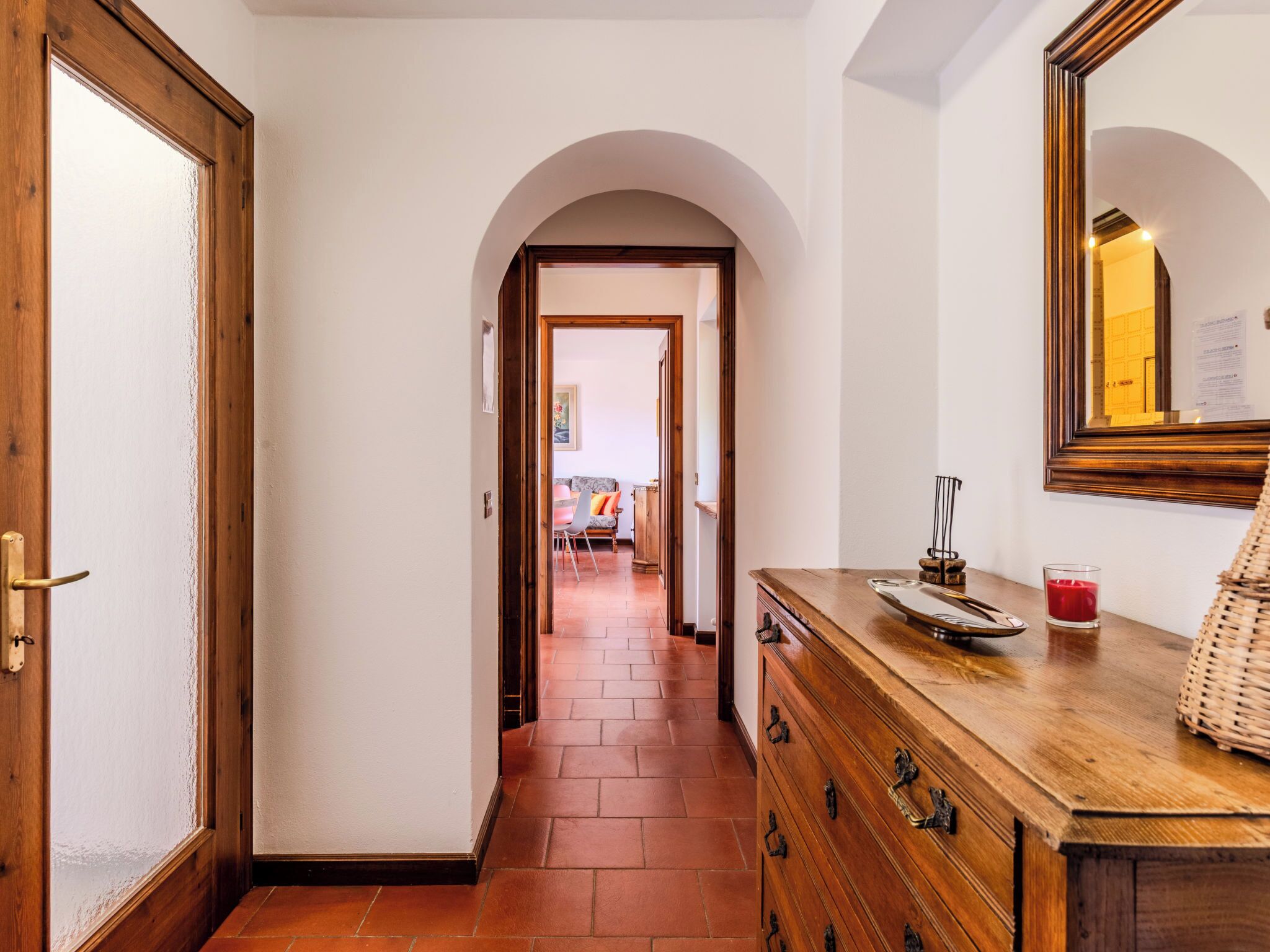 A hallway with a wooden dresser, a mirror, and a door.
