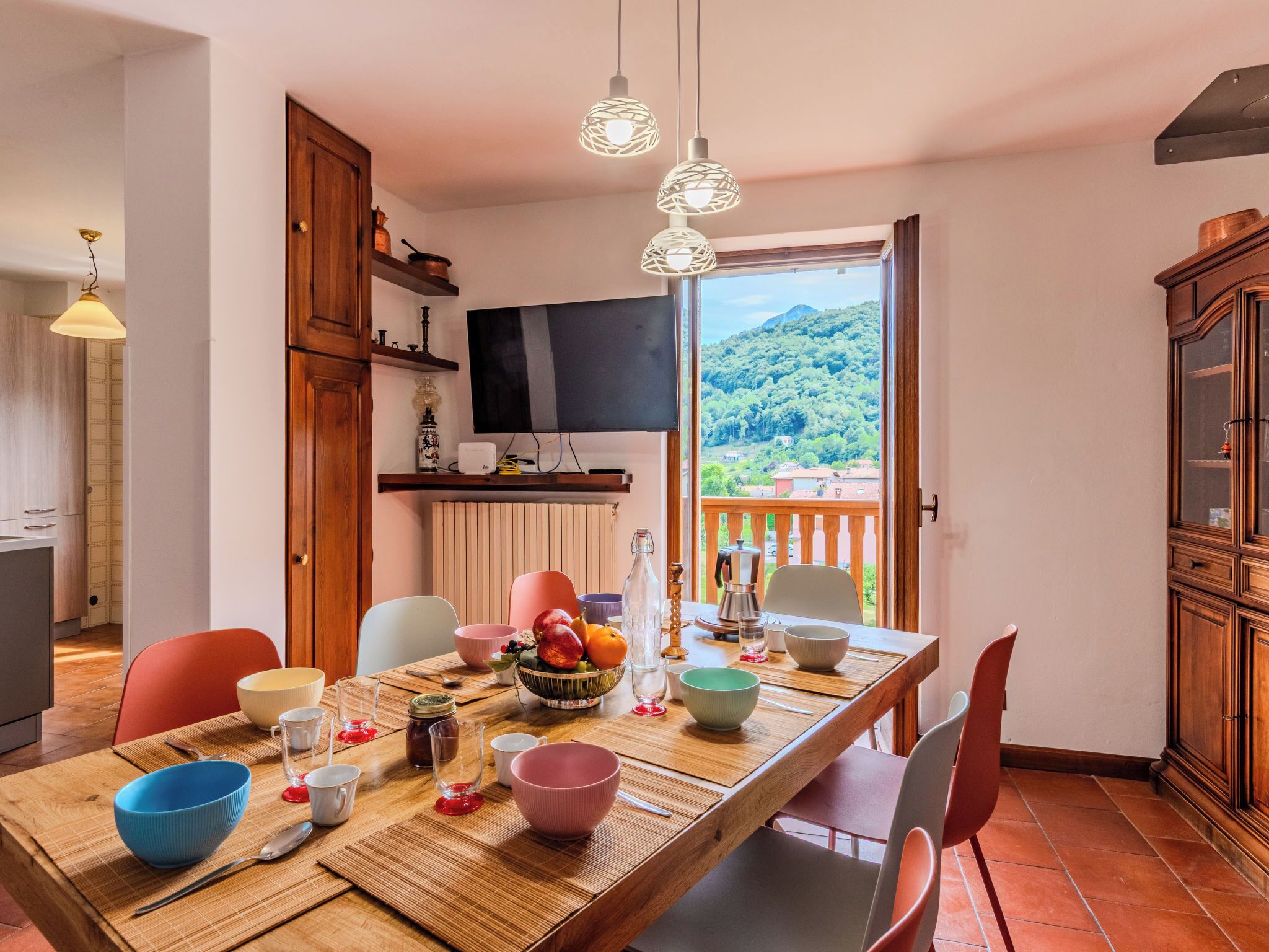 Un coin repas avec une table dressée pour quatre personnes, un téléviseur et une vue sur un paysage montagneux.