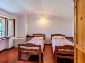 A bedroom with two wooden beds, a nightstand, a dresser, and a window with a view. - Casa Giamba by Interhome (Plesio)