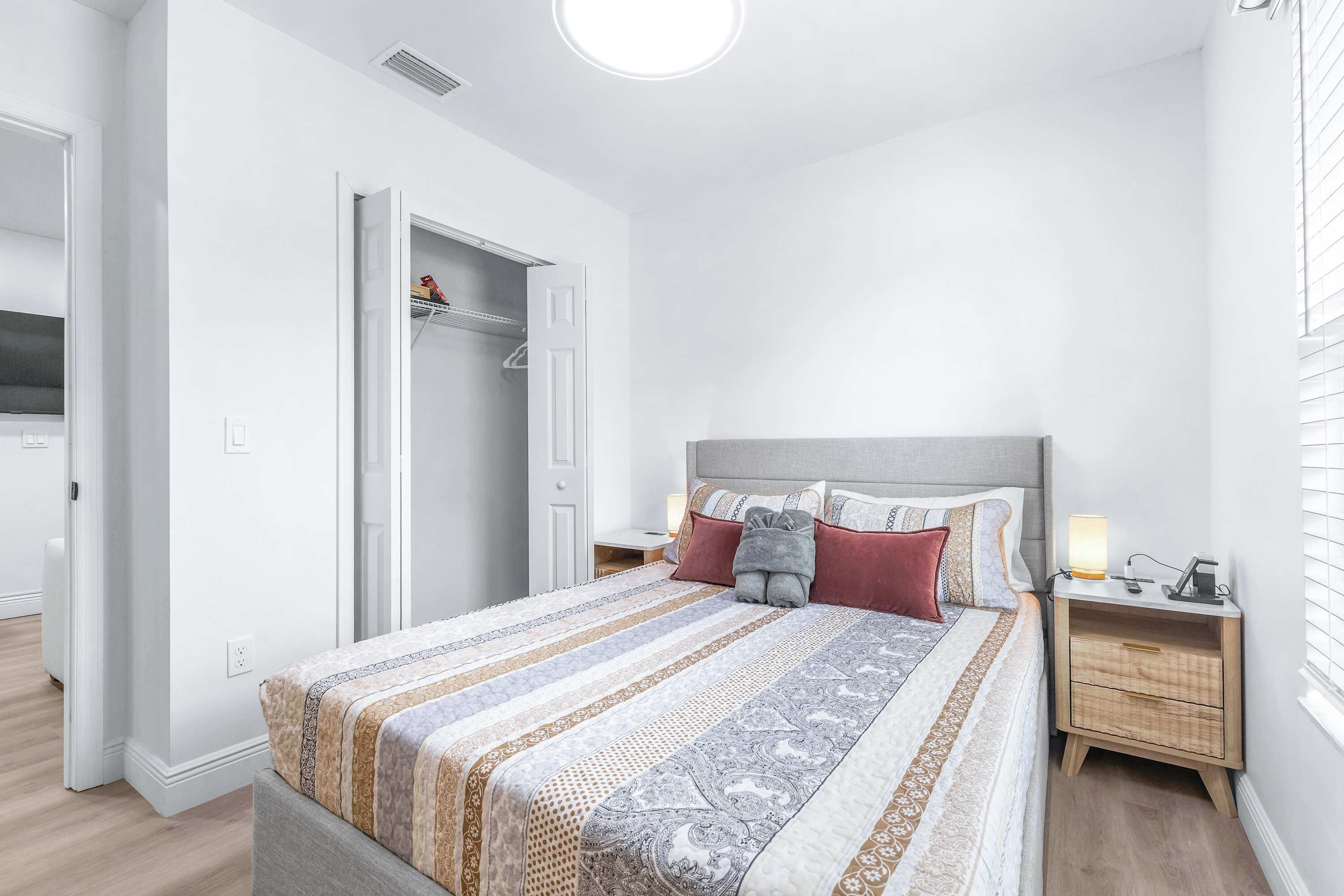 A bedroom with a bed, bedside tables, a wardrobe, and a window with blinds.