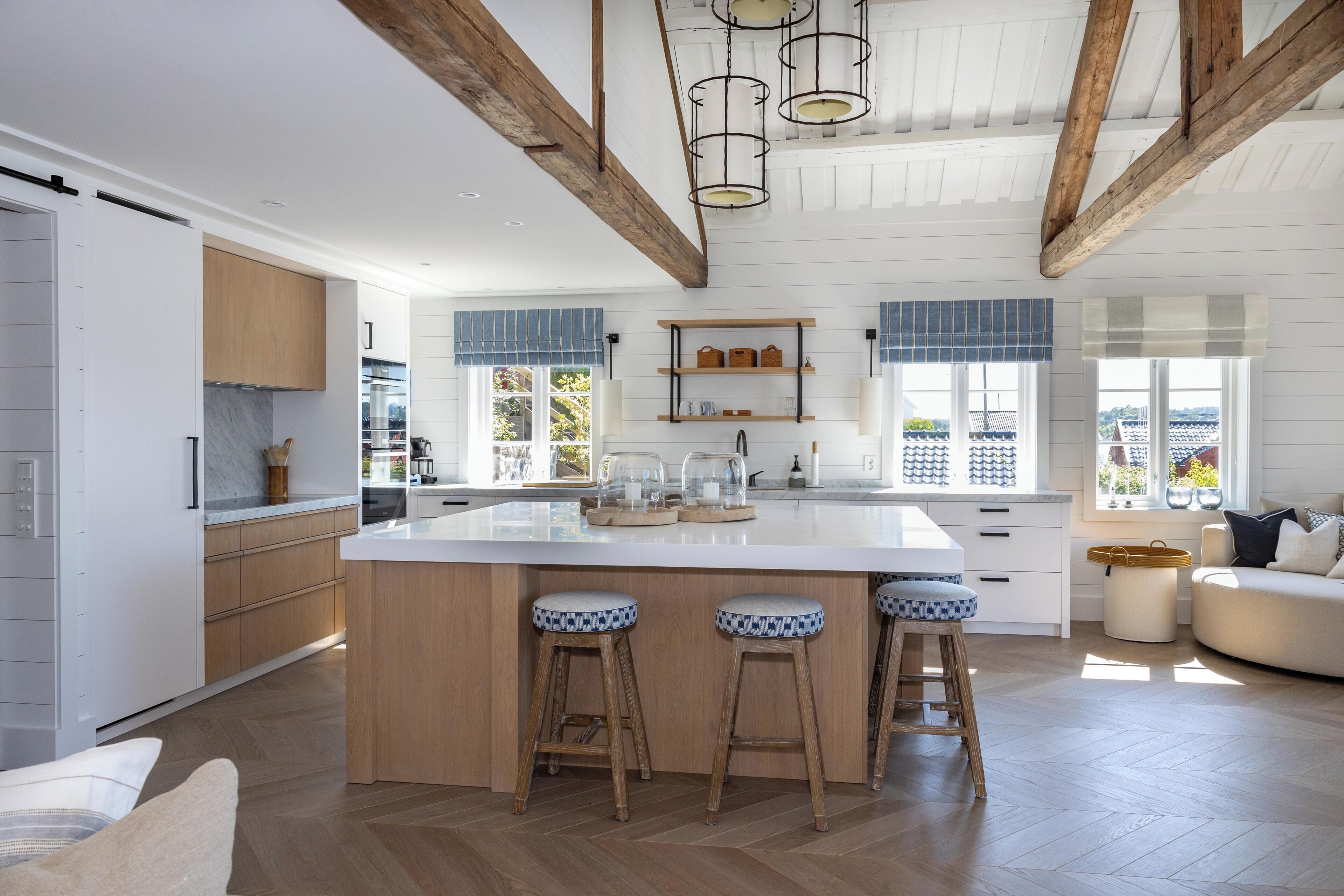 A spacious kitchen with a large island, wooden beams, and a view of the city.
