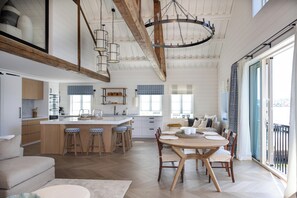 A spacious kitchen with a central island, wooden beams, and a dining area with a large table and chairs.