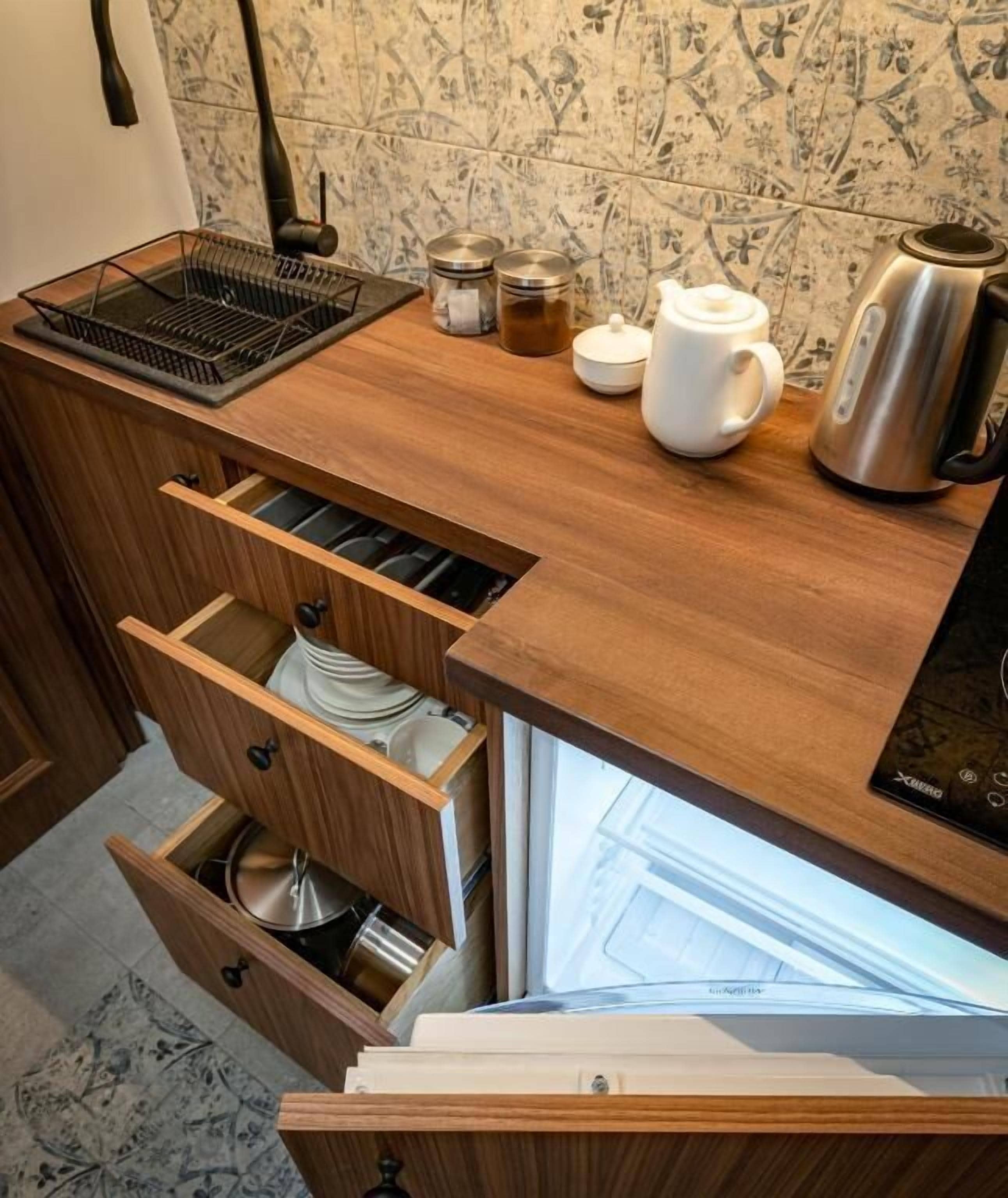 A kitchen with wooden cabinets, a kettle, a teapot, and a coffee maker on the counter.
