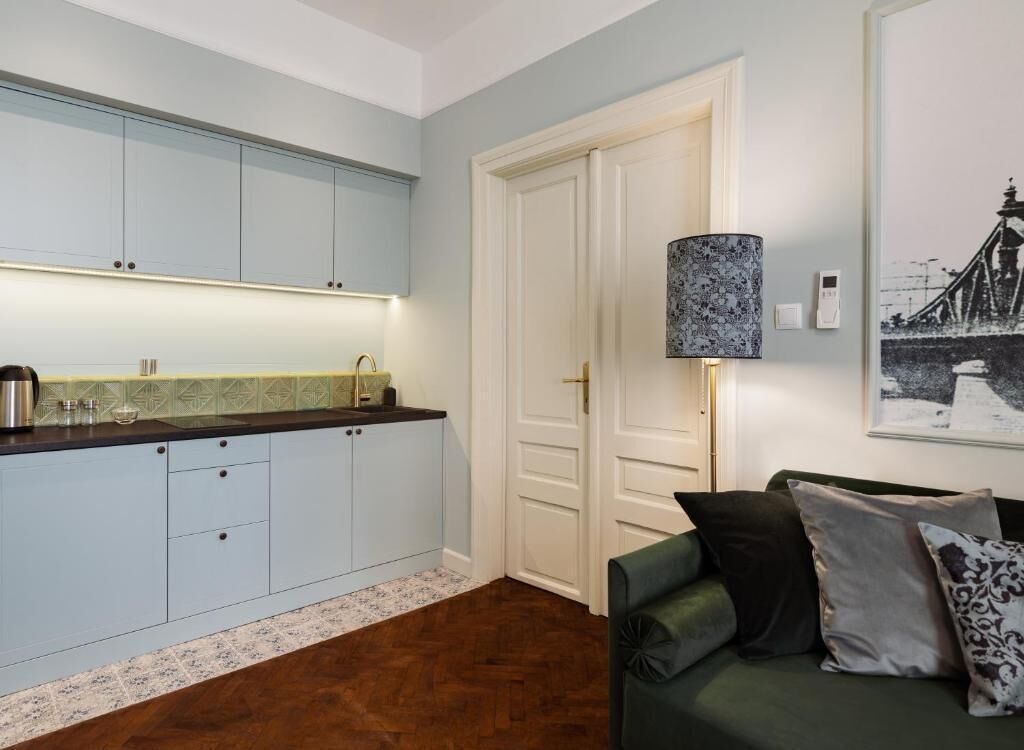 Une cuisine avec des meubles de couleur bleu clair, un plan de travail foncé et un tapis à motifs.