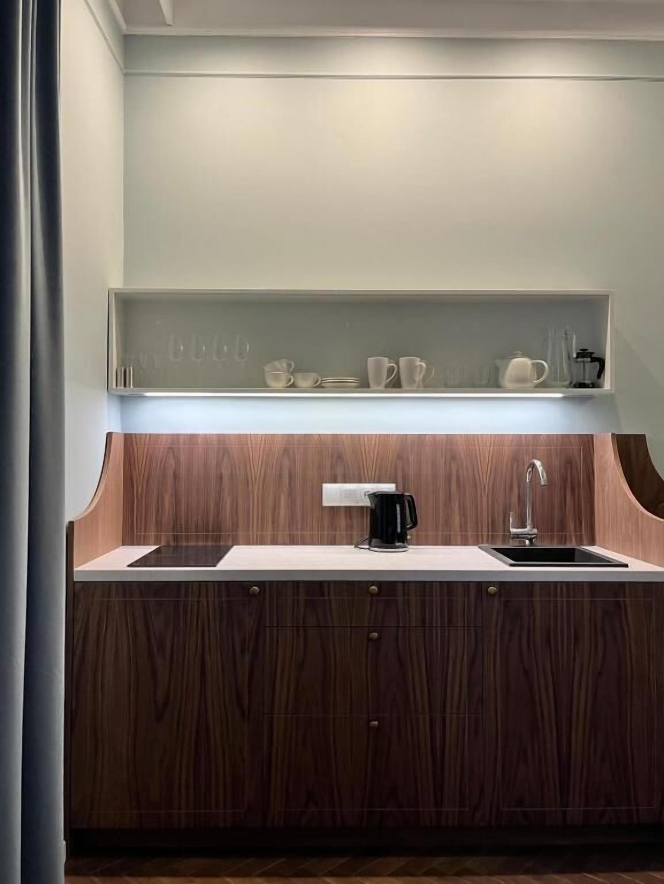 A modern kitchen with a wooden countertop, a sink, and a shelf above with kitchenware.