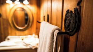 A wooden bathroom with a towel rack, a mirror, and a sink. - Red's cozy rustic cabin 5 min from Cody (Cody)